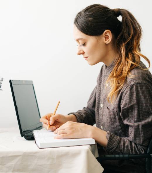 a young woman who works from home while the virus is quarantined on her laptop, studies information on the Internet and writes notes in a diary.A cosy working place,the concept of remote work